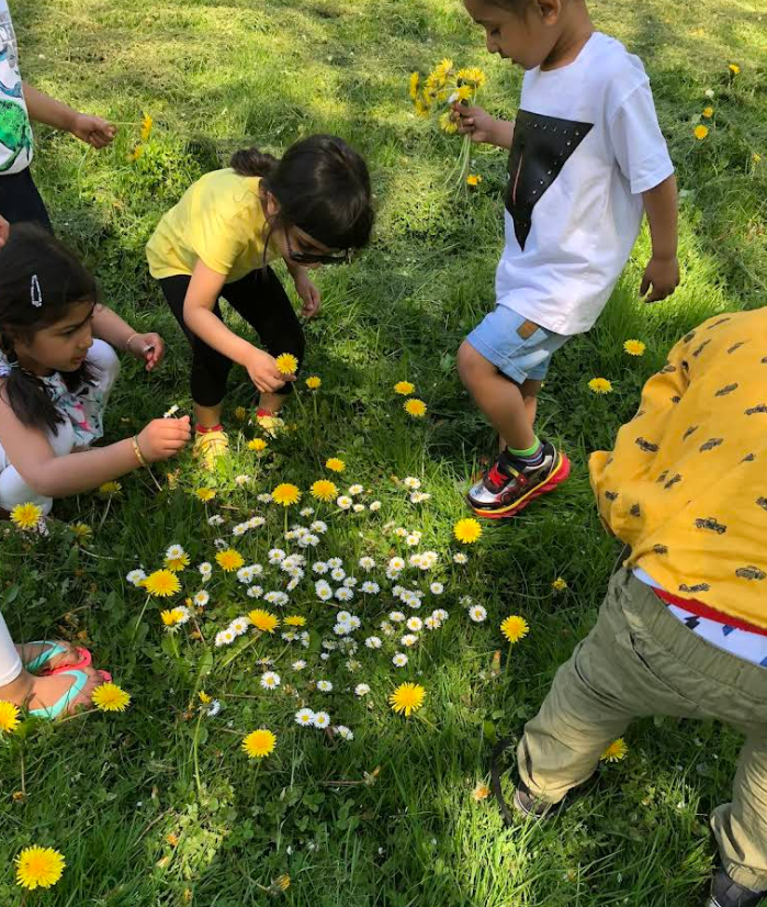 Children picking dandelions and daisies in a sunny meadow