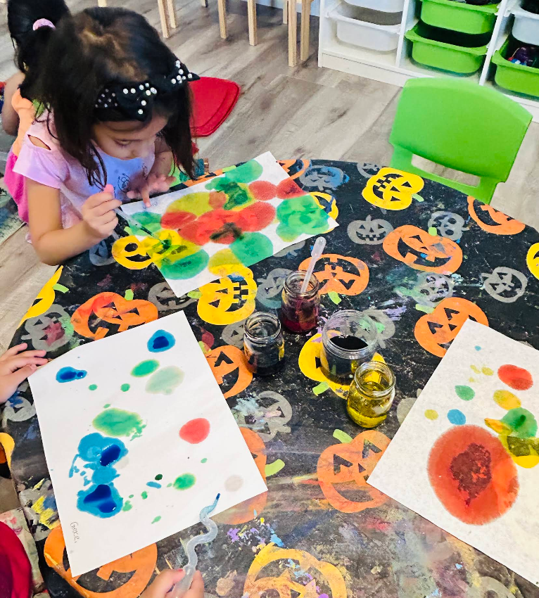 Watercolor dot painting on a pumpkin-patterned table